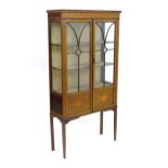 An early 20thC mahogany glazed display cabinet with a moulded cornice above a boxwood inlaid