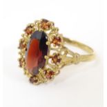 A 9ct gold ring set with a central oval garnet bordered by further garnets. Ring size approx. P
