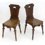 A pair of late 19thC walnut hall chairs stamped 'Gueret Fres, Paris' with shaped tops and incised