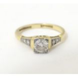 An 18ct gold ring with platinum set central solitaire diamond flanked by two further diamonds to