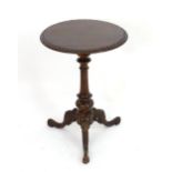 A 20thC mahogany tripod table with a circular carved top above a carved tapering column and three