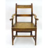 An early 19thC oak open armchair with shaped swept arms and standing on tapering legs united by a