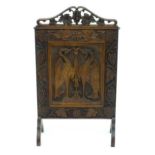 An early 20thC walnut fire screen with a floral pierced bracket to the top above a carved panelled