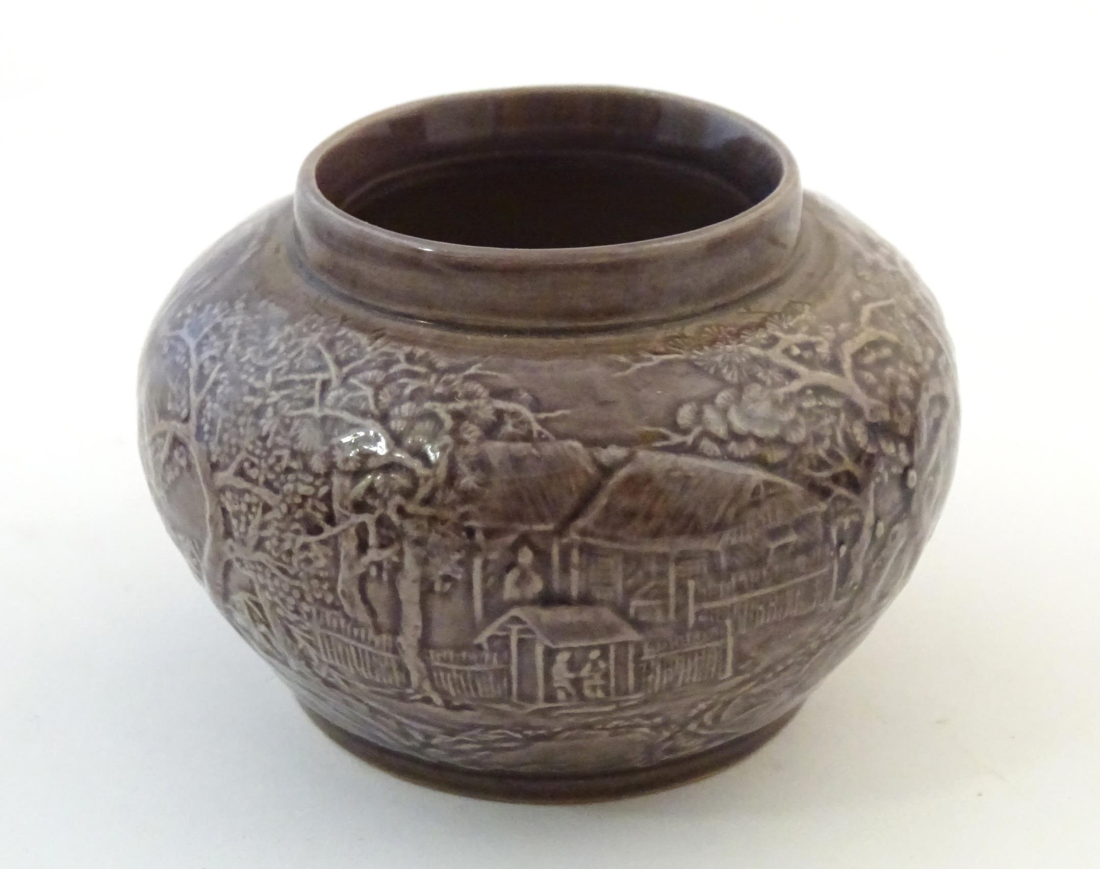 A small Chinese pot of squat form with cast landscape detail. Character marks under. Approx. 2 1/