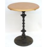 A tall cast iron bar / poseur table with a circular painted top above a cast column and a circular