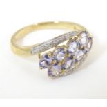 A 9ct gold ring set with tanzanite coloured stones bordered by bands of diamonds. Ring size