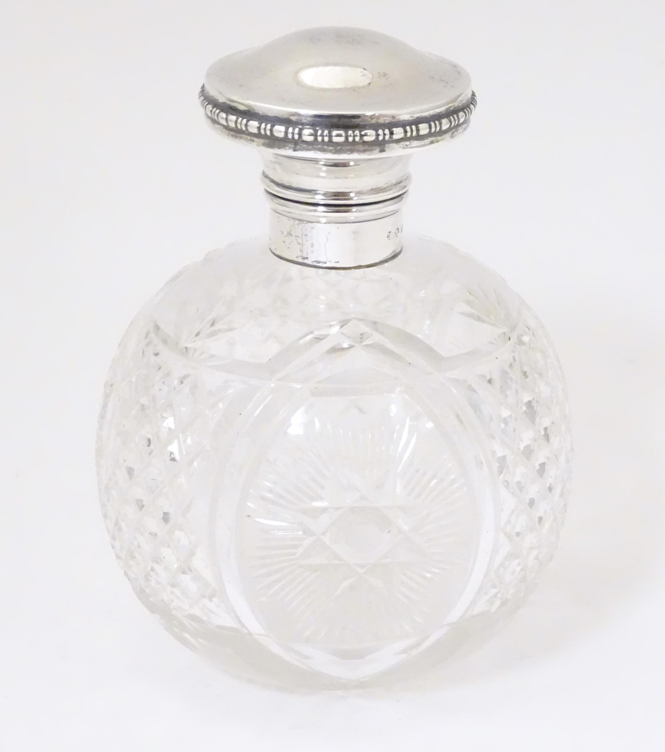 A cut glass scent / perfume bottle with mount and hinged lid, hallmarked Birmingham 1922. Approx.