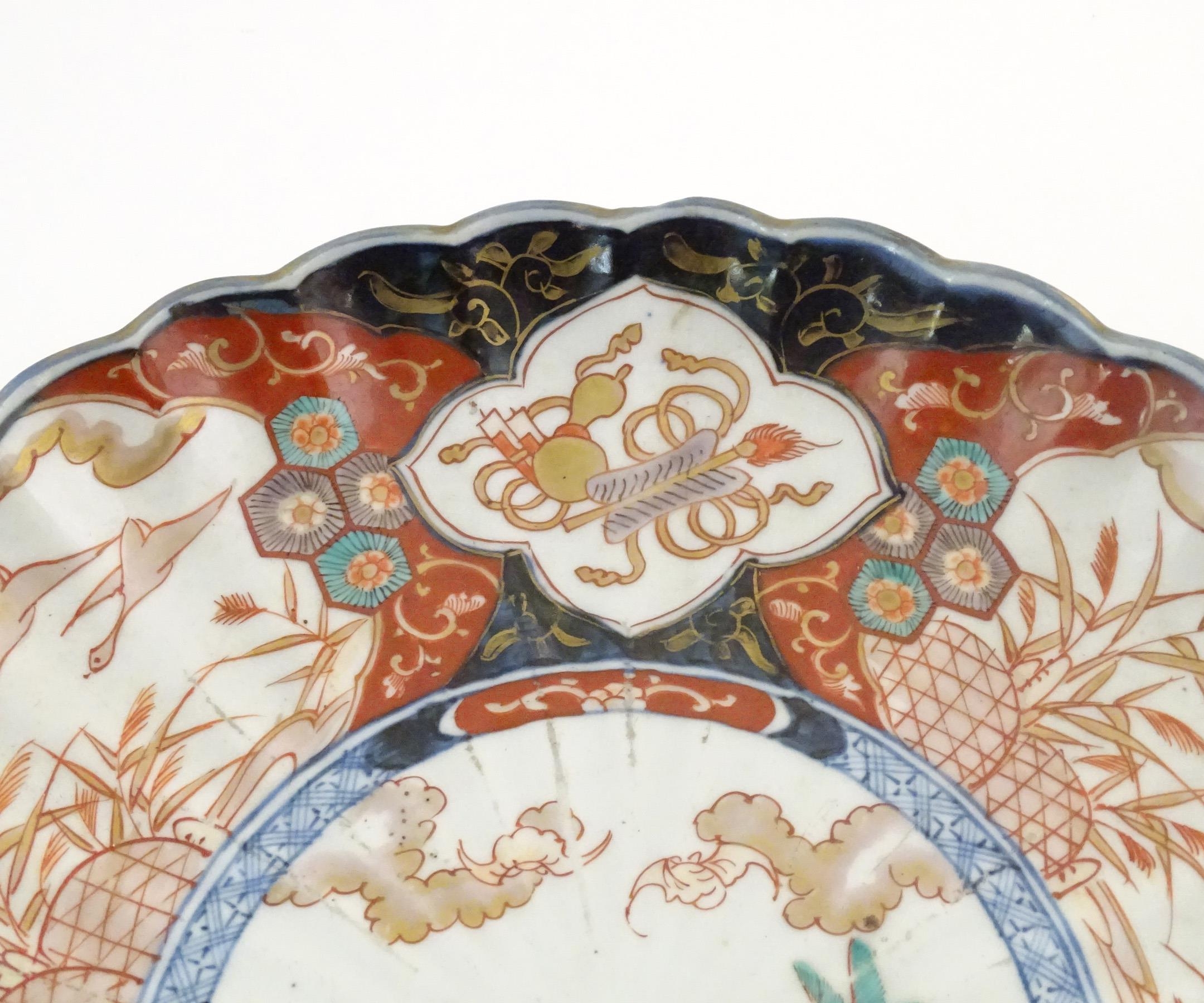 An Oriental charger with scalloped edge in the Imari palette decorated with a stylised censor on - Image 4 of 6