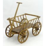 An early 20thC wooden dog cart / garden barrow, with front axel, a draw bar handle, and four wheels.