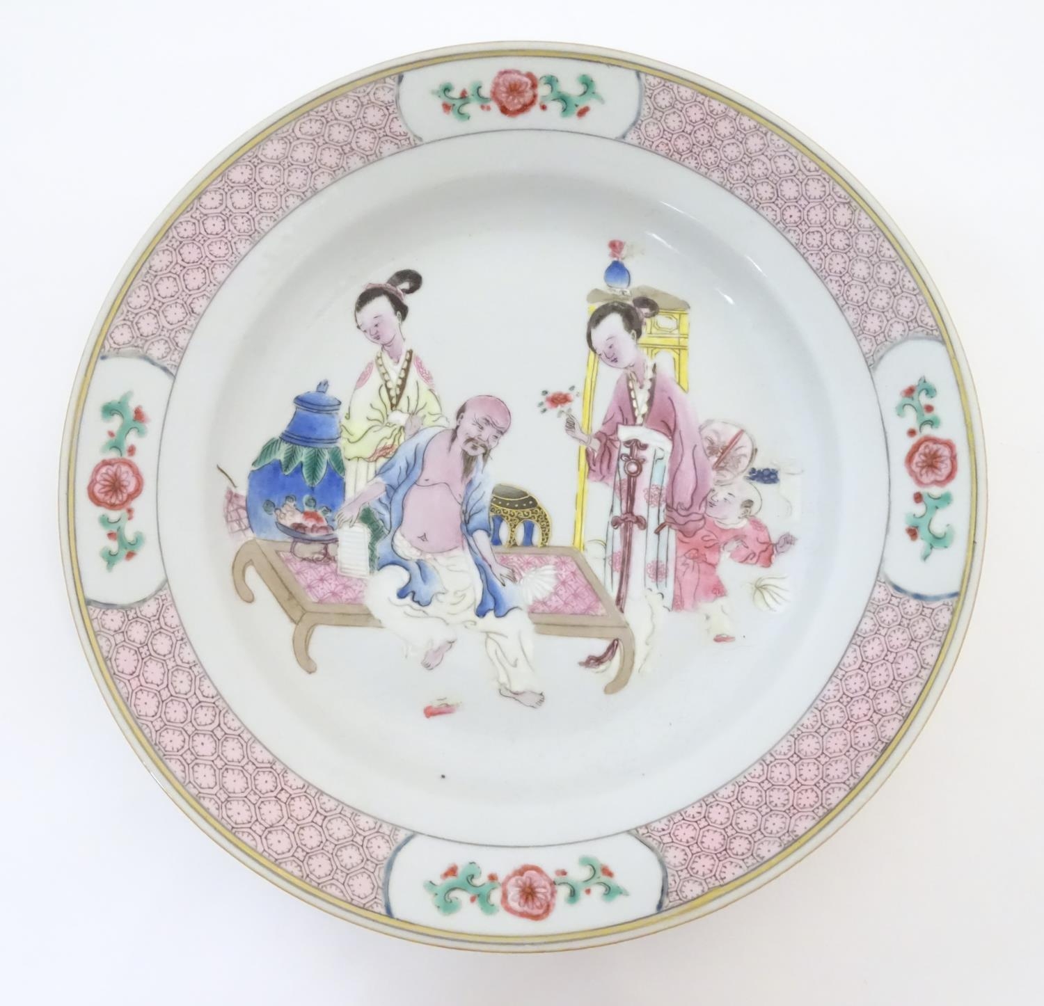 A Chinese famille rose plate decorated with an interior scene with an elderly scholar on a day bed