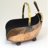 An Arts & Crafts style copper and brass coal scuttle with swing handle, hammered decoration,