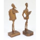 Two 20thC carved wooden models of Don Quixote standing on a stylised book. Approx. 12 1/4" high (