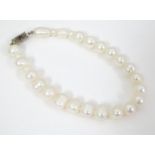 A pearl bracelet with 9ct gold clasp set with black and white diamonds. Approx. 7 1/2" long Please