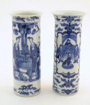 Two Oriental blue and white vases of cylindrical form, one depicting figures in a garden scene
