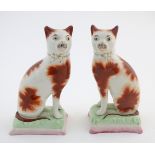 A pair of Victorian Staffordshire pottery cats with gilt bow collar detail. Approx. 7" high (2)