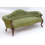 A 19thC walnut sofa with a shaped backrest and deep buttoned upholstery, having a carved frame and a