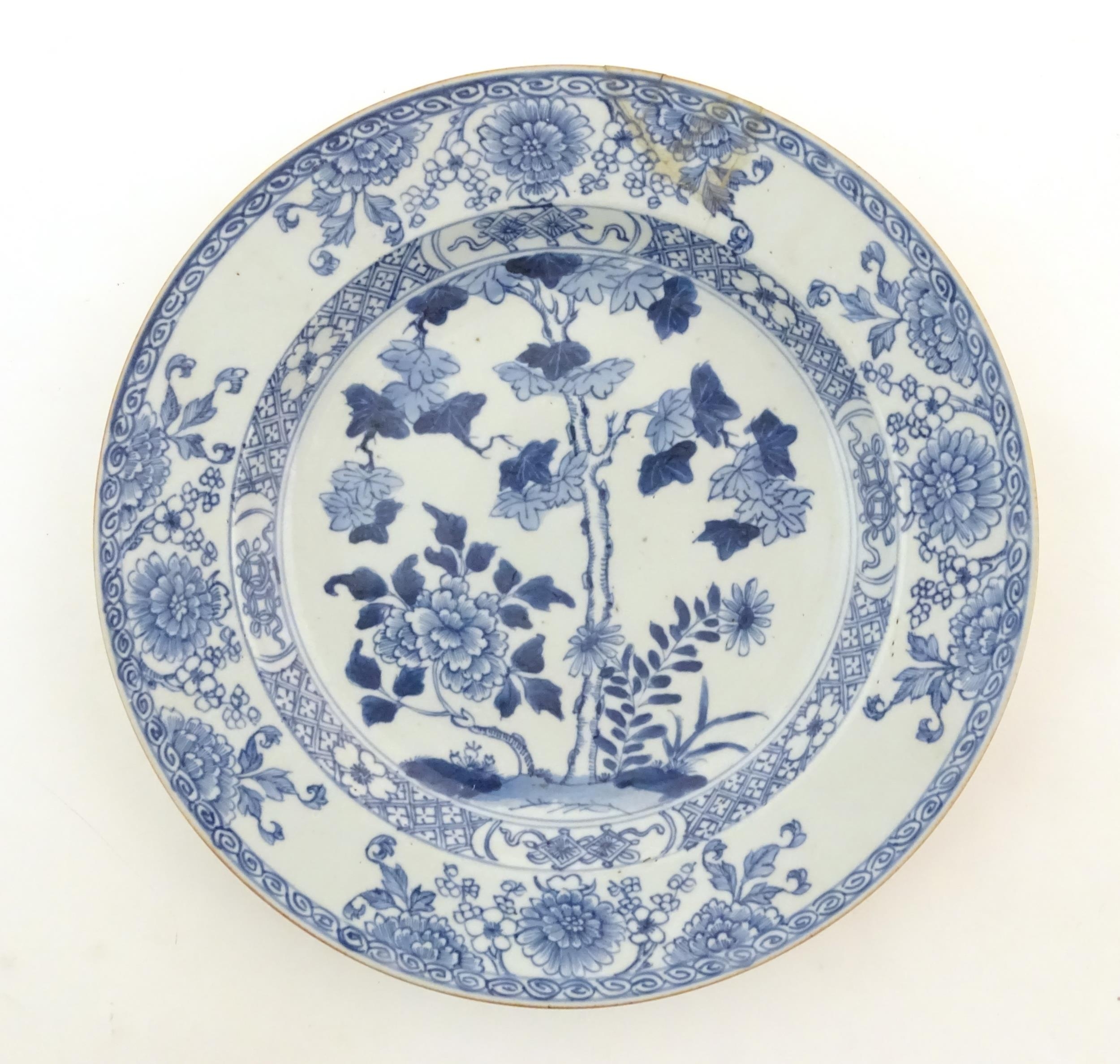 A Chinese blue and white plate decorated with flowers and foliage. With stylised motifs to