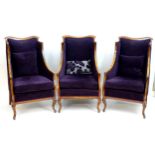 Three 20thC wingback style armchairs with shaped top rails and show wood frames above shaped
