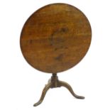 A 19thC oak tripod table with a circular top above a turned tapering column and three cabriole legs.