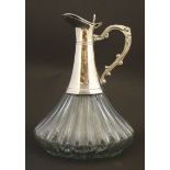 A glass claret jug with lobed decoration and silver plate mounts and handles. Approx 9 1/2" high