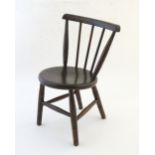An early 20thC child's Windsor chair with a curved back rail and spindle turned supports above