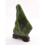 Natural History / Geology Interest: A polished green jade / hardstone specimen on a wooden stand.