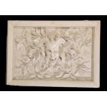 A MOULDED PLASTER RELIEF PANEL DEPICTING A GROTESQUE MASK,