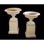 A PAIR OF VICTORIAN WHITE PAINTED CAST IRON GARDEN URNS ON PLINTHS,