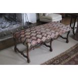 AN UPHOLSTERED AND STAINED WALNUT LONG STOOL,