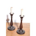 A PAIR OF ITALIAN CARVED AND STAINED WALNUT CANDLESTICKS FITTED AS TABLE LAMPS,