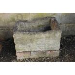 A ROUGH HEWN LIMESTONE TROUGH,