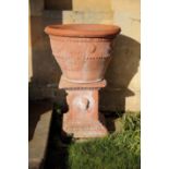 TWO SIMILAR TERRACOTTA GARDEN URNS ON PLINTHS,