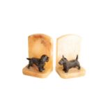 A PAIR OF CONTINENTAL PAINTED METAL MOUNTED ONYX BOOKENDS MODELLED WITH DOGS,