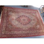 A LARGE RED GROUND PERSIAN DESIGN CARPET
