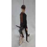 A 'FOLK ART' JOINTED TIN FIGURE ON A 'PENNY FARTHING' BICYCLE