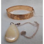 A ROLLED GOLD HINGED BANGLE AND A MOTHER OF PEARL PENDANT