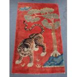 A CHINESE RUG, RED GROUND DECORATED WITH A TIGER