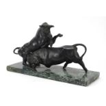 Patinated bronze study of two stylised fighting bulls raised on a rectangular green marble base,