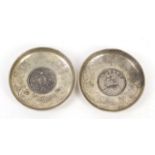 Two Chinese silver coloured metal coins dishes, each 9cm in diameter