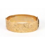 9ct gold bronze core hinged bangle engraved with flowers, 6.5cm wide, 51.0g