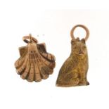 Two unmarked gold coloured metal charms comprising seated cat and clam shell, the largest 1.3cm