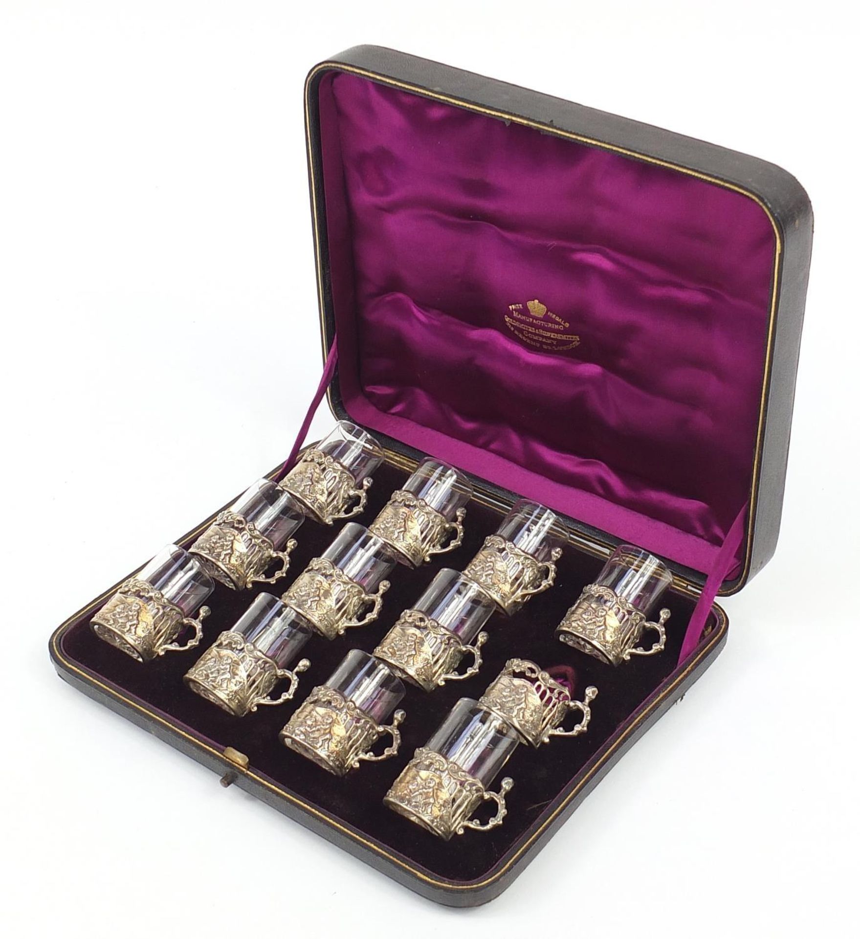 Set of twelve Victorian silver glass holders embossed with cherubs at play and fitted with eleven