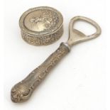 Oval silver pill box embossed with Putti and a silver handled bottle opener, 12.5cm in length, total