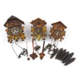 Three carved Black Forest cuckoo clocks with weights and pendulums, the largest 24.5cm high
