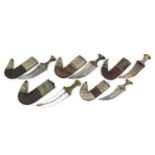 Five Omani horn handled Jambiya daggers with leather sheaths having applied silver coloured metal