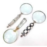 Three magnifying glasses including an example with chequered design handle, the largest 26cm in