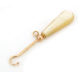 Unmarked gold and mother of pearl button hook (tests as 9ct gold), 6cm in length, 3.5g