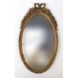 Ornate gilt framed wall mirror with bow crest, 72cm x 42cm :