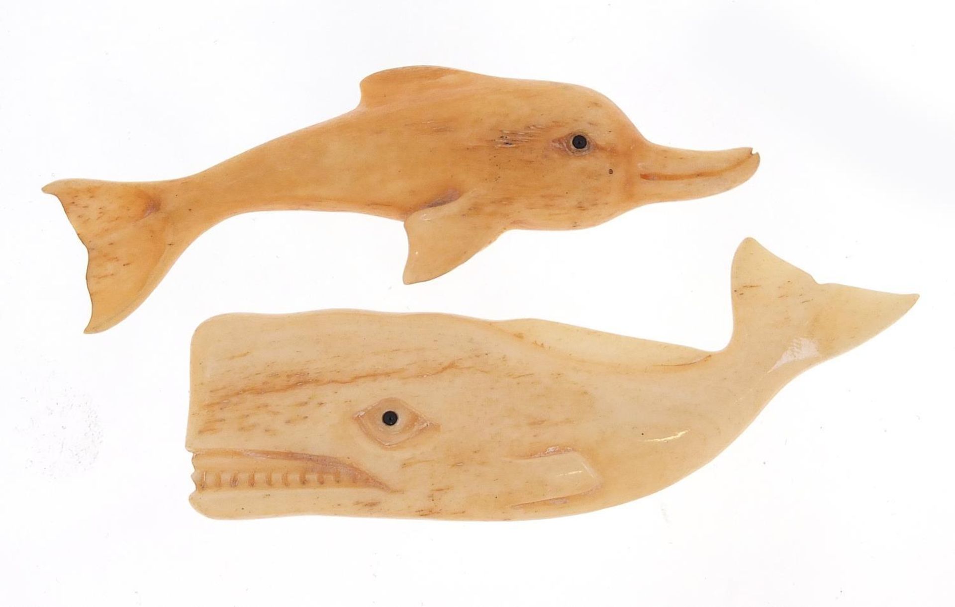 Two Scrimshaw style bone carvings of a whale and dolphin, the largest 8cm in length :