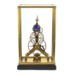 Gothic style brass skeleton clock with moon face dial and glass display case, with key and pendulum,